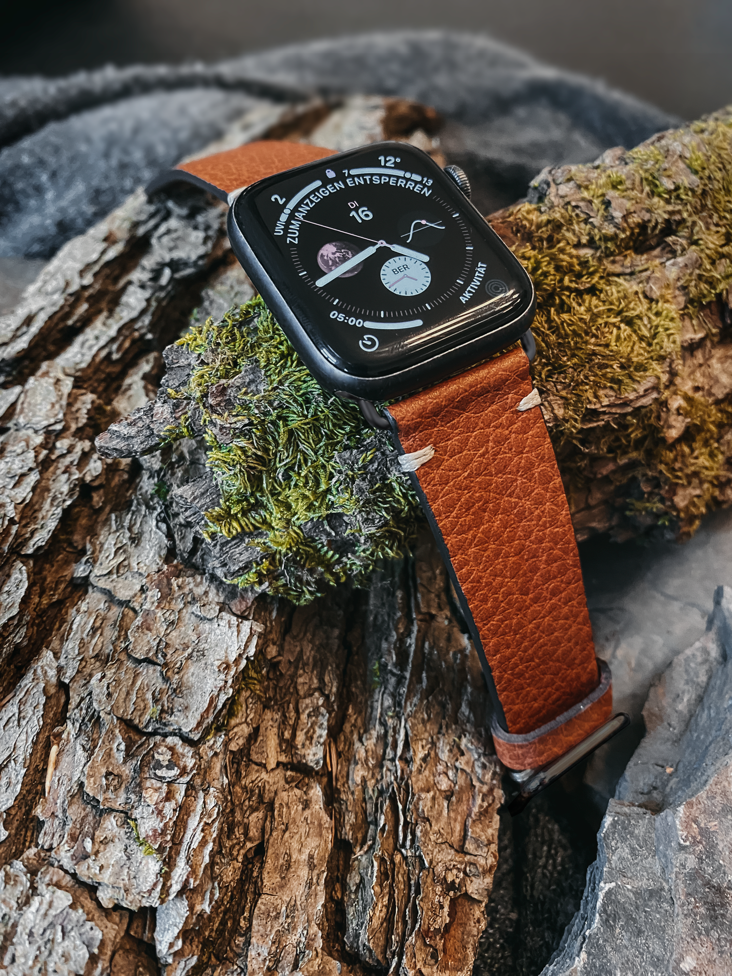  Veganes Apple Watch Armband aus Lederimitat von Bionti in der Farbe Cinnamon liegt auf einem Stück Rinde